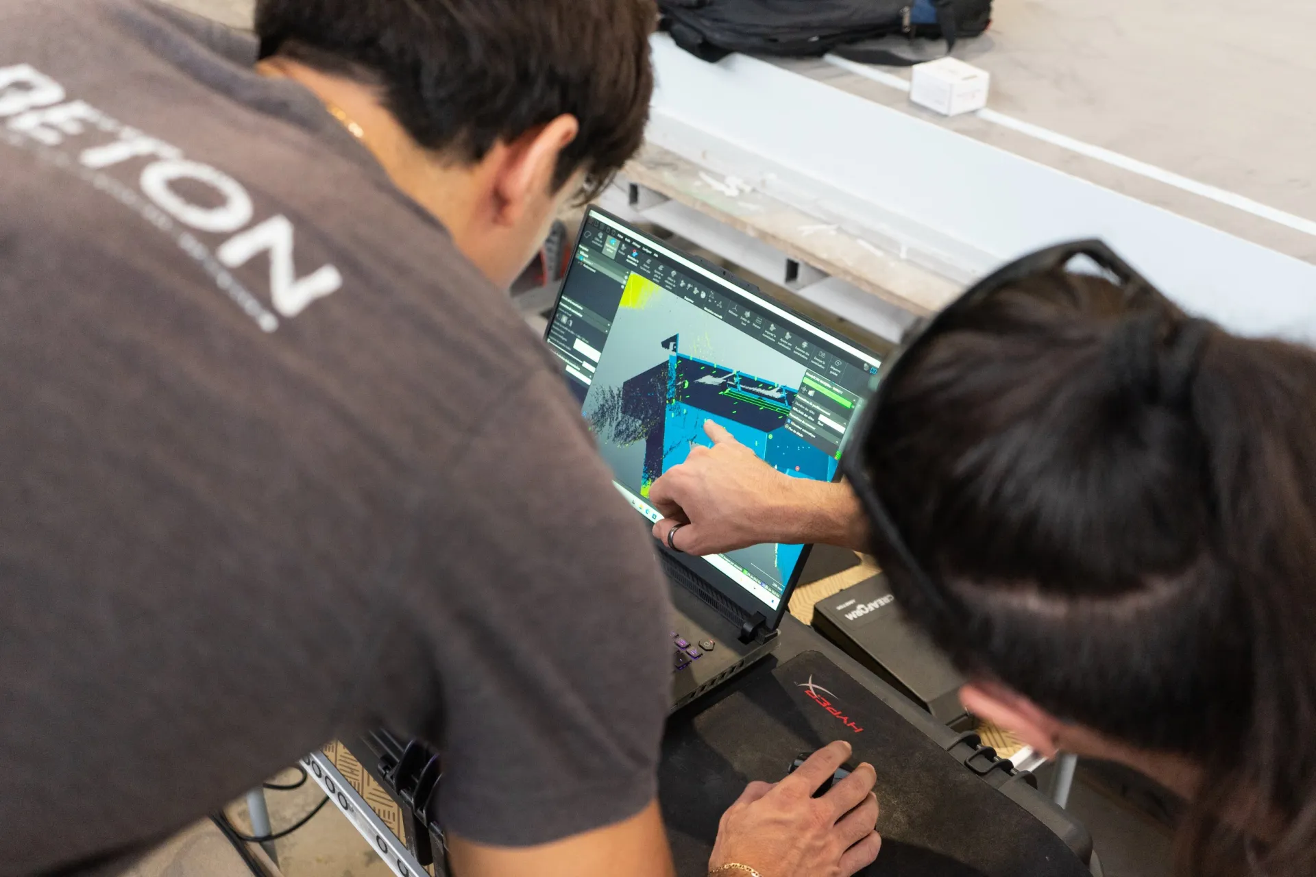 Zwei Mitarbeiter von Innobéton prüfen in der Werkstatt ein digitales 3D-Modell auf einem Laptop